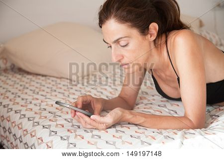 Woman Lying On The Bed With Smartphone