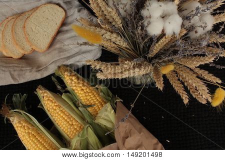 yellow corn, lavender, bread on black background