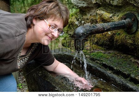 Woman enjoys cold arm bath by Kneipp