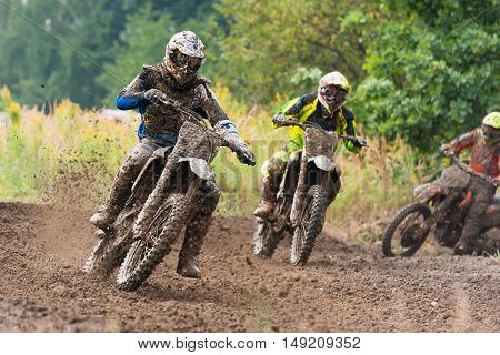 Motocross riders in the race on mud road