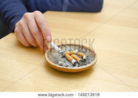 Female hand with cigarette rest on the ashtray