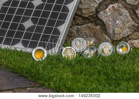 solar panel and various E27 bulbs LED halogen and tungsten bulbs some on the grass ( selective focus )