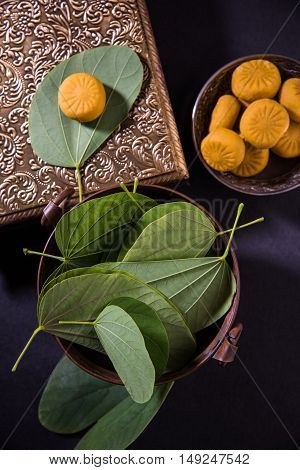 indian festival dussehra or vijayadashmi or ayudh puja, showing apta leaf or Bauhinia racemosa with traditional indian sweets pedha in silver bowl