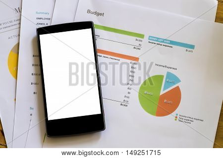 smart pone over stock maket chart on wood desk. vintage effect. Smartphone with blank screen and can be add your texts or others on screen.