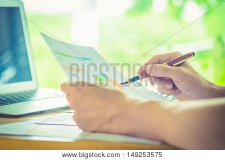 hand hold fountain pen pointing stock maket paper in office. vintage effect.
