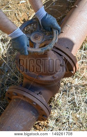 Workman at work in an old plumbing with equipment. Closure of the pipeline valve