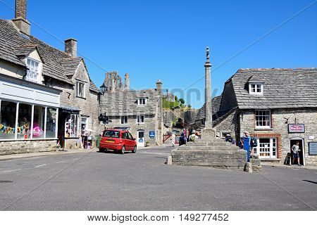 CORFE, UNITED KINGDOM - JULY 19, 2016 - Stone cross in the village centre with the castle to the rear Corfe Dorset England UK Western Europe, July 19, 2016.