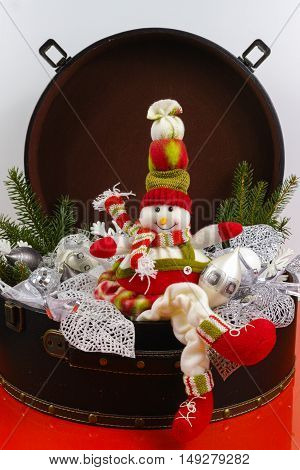 Funny snowman sits on vintage brown coffer with white christmas tree decoration copy space