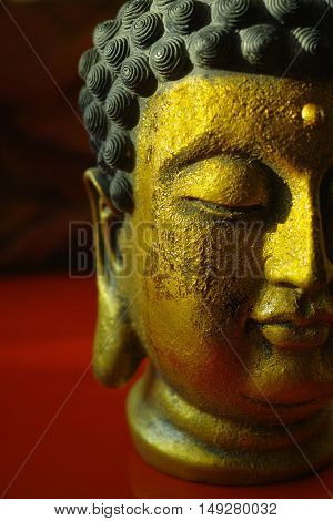 Gold Buddha face on dark red background