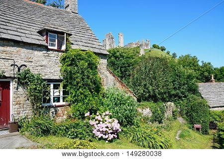 CORFE, UNITED KINGDOM - JULY 19, 2016 - Pretty stone cottage with the castle to the rear Corfe Dorset England UK Western Europe, July 19, 2016.
