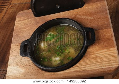 Cooked meat dumplings (pelmeni, chuchpara) in a black pan. wooden background.