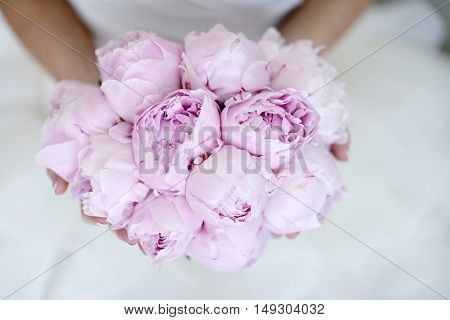 Beautiful bride is holding a wedding colorful bouquet. Beauty of colored flowers. Close-up bunch of florets. Bridal accessories. Female decoration for girl. Details for marriage and for married couple