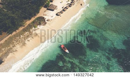 Top view aerial photo from flying drone of a wonderful nature landscape with sandy beach with beautiful coral bottom for snorkeling. Indian Ocean seascape with beautiful calm waves. Fisherman boat