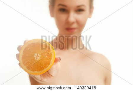 Young woman holding half an orange in front of her. White background