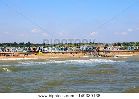 Crowded beach at Southwold with a row of beach huts in the background