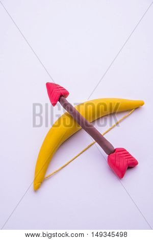 model of bow and arrow favourite weapon of lord Rama or Arjuna, made up of play dough or playdough or colourful clay, selective focus isolated over white background