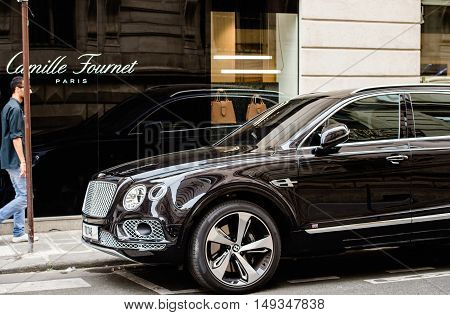 PARIS FRANCE - MAY 21 2016: Man admiring the luxury Bentley Bentayga Hybrid SUV on the streets of Paris France