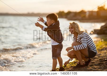 Beautiful woman with a child of four years playing on the beach near the sea