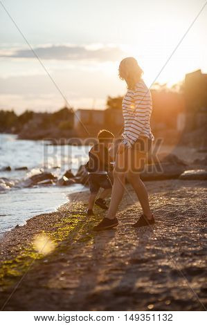 Beautiful woman with a child of four years playing on the beach near the sea