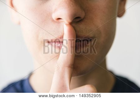 Boy doing a silence gesture against white background