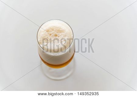 Glass of fresh lager beer on white table