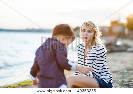 Beautiful woman with a child of four years playing on the beach near the sea