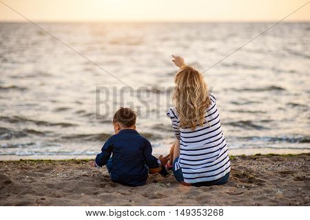 Beautiful woman with a child of four years playing on the beach near the sea