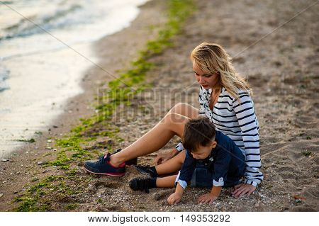 Beautiful woman with a child of four years playing on the beach near the sea