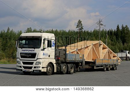 ORIVESI, FINLAND - SEPTEMBER 1, 2016: White MAN TGX 26.480 semi truck transports roof truss on flat trailer.