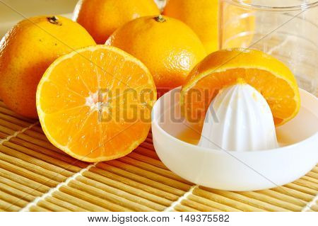 oranges with Reamer juicer on bamboo mat