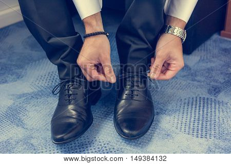 Groom tying shoelaces. Final wedding preaprations closeup.