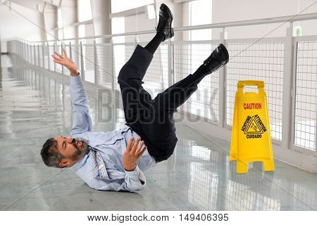 Hispanic businessman falling on wet floor inside office building