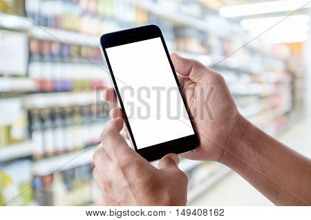 Hand holding blank screen of smartphone device in supermarket.