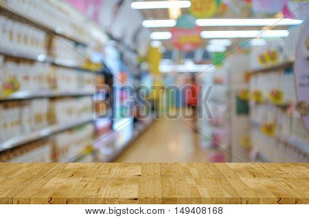Empty wooden table and corridor in Supermarket blur background with bokeh image for product display montage.
