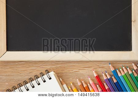 color pencils with notebook and a blackborad