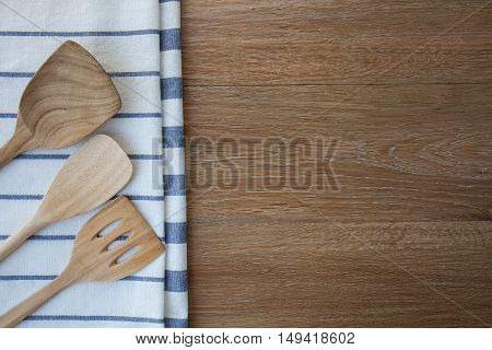 Wooden kitchen utensils and linen kitchen towels on dark wood tabletop with copy space in the center