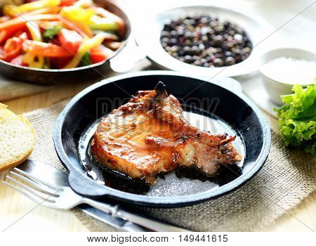 pork steak in a frying pan, fried vegetables