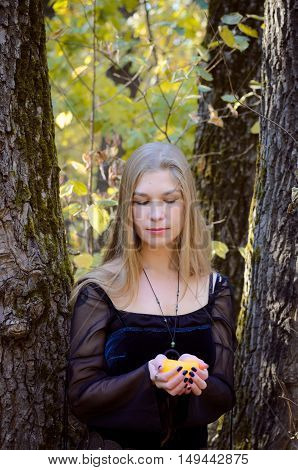 Young Girl In A Fantasy Long Black Dress Posing In An Autumn Forest