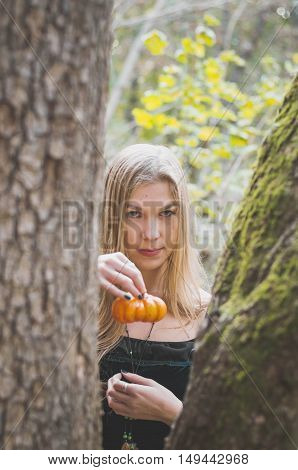 Blond long-haired girl in a fantasy black dress in an autumn forest scary halloween fairy tale