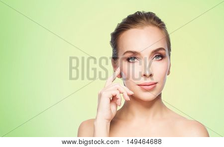 beauty, people and plastic surgery concept - beautiful young woman showing her cheekbone over green background
