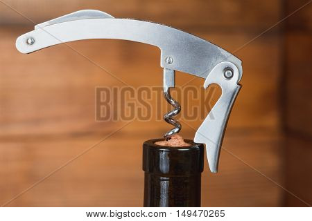 Opening a bottle of red wine metal corkscrew, macro bachground