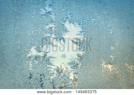 Frozen window at cold time. Iced surface. Frosty abstract background. Glass with the thawed hole