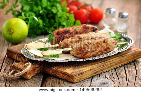 Homemade meat kebabs skewers with dogberry and onion salad on wooden background.