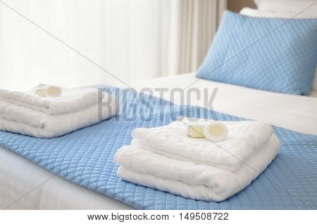 Bed with fresh towels and amenities in bright lit room