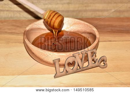 Honey in wood bowl and love with wood background