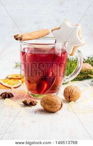 Homemade butter nuts star shaped cookie with icing pine orange slicescinnamon anise walnuts and golden ribbon over white wood background. A cup of berry tea. Christmas decoration.