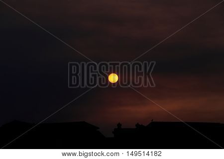 Summer sunset and orange sun over dramatic red clouds
