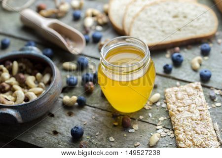 Honey in glass jar on natural wooden table.