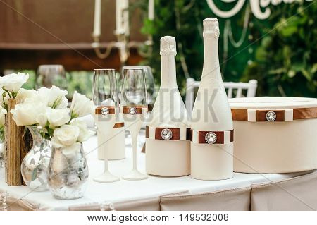 Wedding event. Chiavari chairs on the covered wooden deck. On a table decorated with a bottle of champagne and glasses. On the table box for gifts.