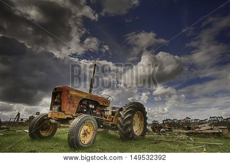 Vintage tractor in field against a dynamic cloudy blue sky background